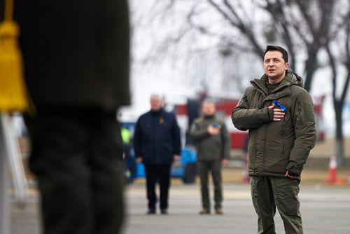Ukrainian President Volodymyr Zelenskyy listens to Ukrainian national anthem as he takes part in celebration of the Day of the Unity at an international airport outside Kyiv, Ukraine, Wednesday, February 16, 2022