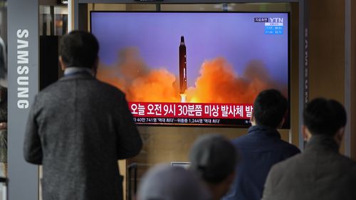People watch a TV screen showing a news program reporting about North Korea's missile with file footage, at a train station in Seoul, South Korea. 