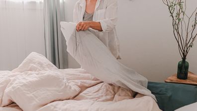 Woman making her bed changing pillowcase