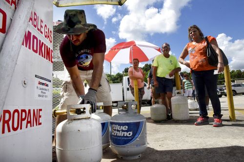 Gustavo Galindo, left, fills propane tanks at an Exxon gas station in Davie, Florida. (AP)