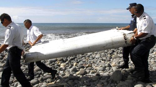 Investigators carry a piece of debris washed ashore on LaReunion Island.