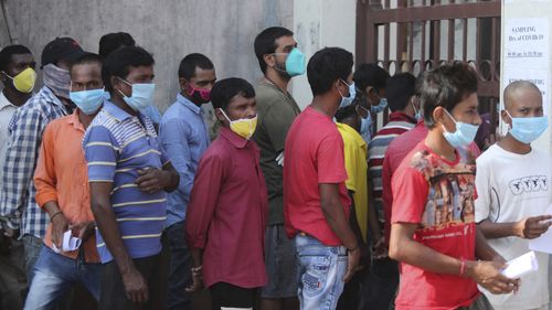 People wait in a queue to register their names to have their nasal swab samples taken to test for COVID-19 at a government hospital in Jammu, India.