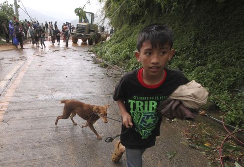 A boy evacuates to safer ground with his pet dog as workers try to clear a landslide that occurred in Itogon township, Benguet province.