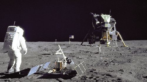 Astronaut Buzz Aldrin standing beside a lunar seismometer, covered with a dust detector invented by Prof O'Brien from Perth.