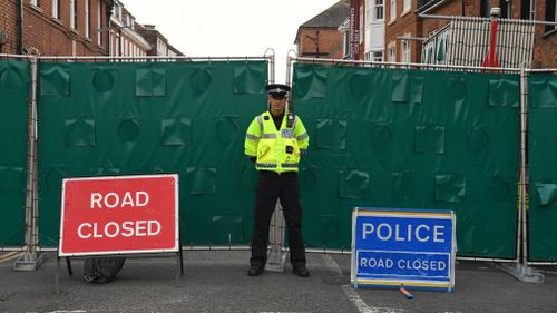 A police officer stands in front of screens erected in Rollestone Street, Salisbury, Wiltshire. Picture: AAP