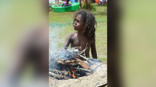 Two-year-old Roy Noble helped his father Danton Noble, 30, break sticks for a BBQ fire at Australia Day or Survival Day events at Yarrabah. (AAP)