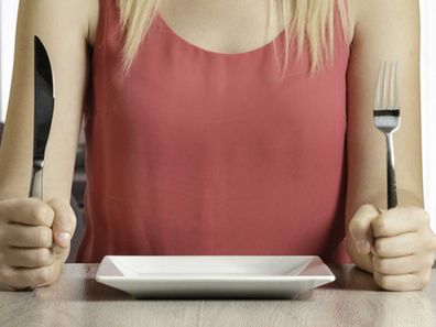 Fasting woman with empty plate, hungry