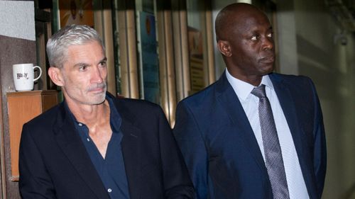 Former Australian soccer captain and commentator Craig Foster, left, and vice-president of FIFPro Francis Awaritef wait outside the Bangkok court.