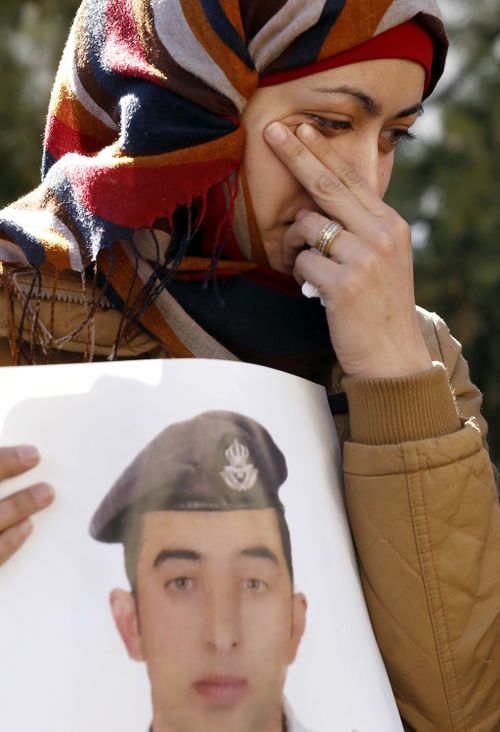 Anwar al-Tarawneh, the wife of the Jordanian pilot, holds a poster of him as she weeps during a protest. (AAP)