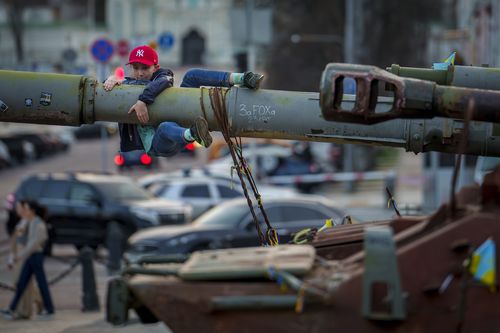 A boy holds on to the barrel of a tank, part of a display of destroyed Russian military equipment, in Kyiv, Ukraine, Sunday, March 31, 2024.