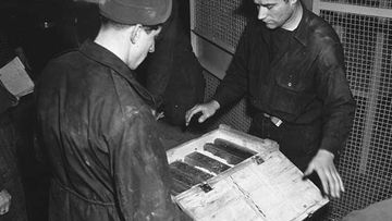 Workers inspect gold bars taken from Jews by the Nazis. (Getty Images)