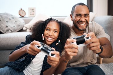 Dad playing video games with daughter.