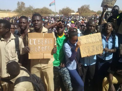 Burkinabes hold signs asking for the Elliots to be freed. (9NEWS)