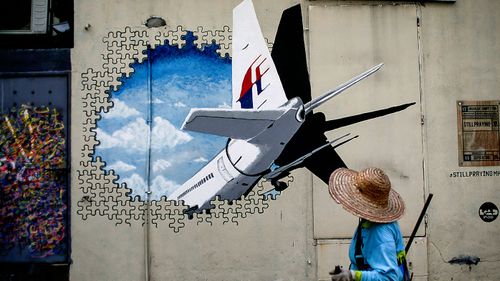 A man walks in front of a Malaysia Airlines flight MH370 mural painted on a wall at a street in Shah Alam, outside Kuala Lumpur, Malaysia. (Photo: AP).