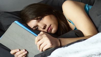 A woman using an iPad in bed