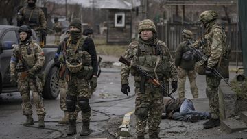 Ukrainian servicemen stand surrounding the body of man dressed in civilian clothing, in the formerly Russian-occupied Kyiv suburb of Bucha. 