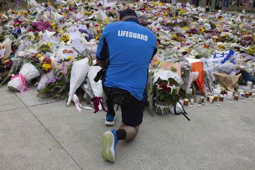 A Surf lifesaver places flowers at the memorial for the Bondi Beach shootings in front of the Bondi Beach Pavillion, Bondi Beach, Sydney, 16 December 2025.. Photo: Jessica Hromas