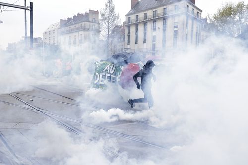 Youths run though tear gas during a protest Thursday, April 6, 2023 in Nantes, western France. 