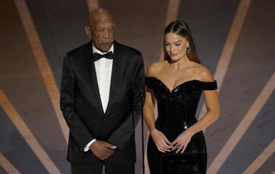 Morgan Freeman, left, and Margot Robbie speak about Warner Brothers 100 years anniversary at the Oscars on Sunday, March 12, 2023, at the Dolby Theatre in Los Angeles. (AP Photo/Chris Pizzello)