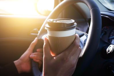 Man holding coffee in car