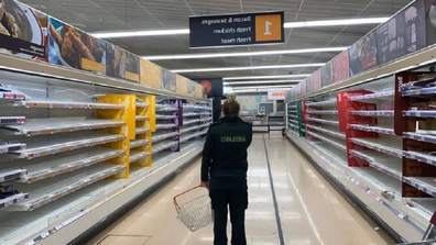 Paramedic staring at empty shelves in a supermarket in the UK.