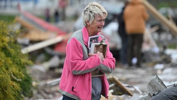 Debbie Lowdermilk holds photographs as she reacts while looking at the destroyed school she owns the day after a tornado hit Sullivan, Indiana, US April 1, 2023.  