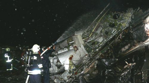 Firefighters spray water on the wreckage of a TransAsia Airways plane on the Penghu Islands in the Taiwan Strait on 23 July 2014. (AAP)