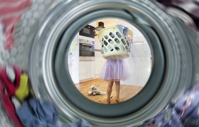 Girl carrying basket of clothes to washing machine