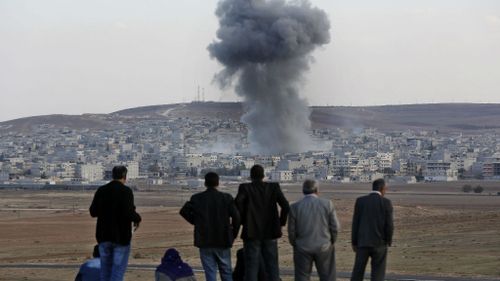 Locals watch on as US-led air strikes rain down on Kobane. (AAP)