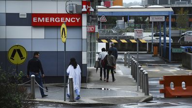 A group of three people walk towards the emergency entrance at Westmead Hospital, Westmead, NSW. 
