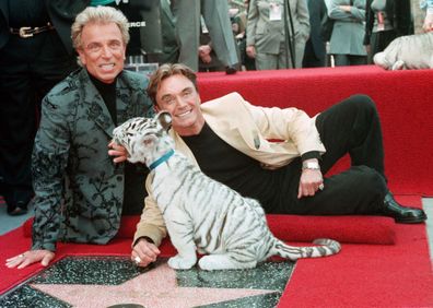 Illusionists Siegfried Fischbacher, left and Roy Uwe Ludwig Horn pose for photographers with a white tiger cub after they unveiled their star on the Hollywood Walk of Fame in Los Angeles, Calif., on Sept. 23, 1994