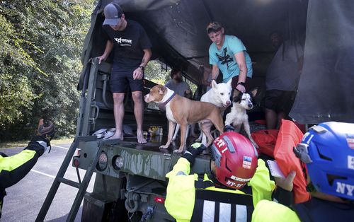 New York Urban Search and Rescue team members help residents get off of a truck after being evacuated.