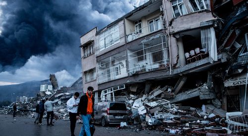People walk past collapsed buildings in Iskenderun, Turkey.