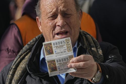 A man holds up a Christmas lottery ticket he is selling in Madrid, Spain, Wednesday, Dec. 20, 2023 