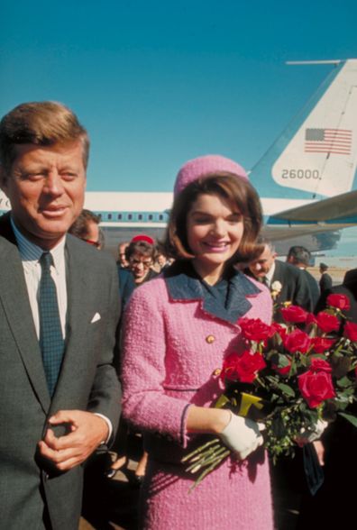 President John F. Kennedy and his wife Jackie, who is holding a bouquet of roses, just after their arrival at the airport for the fateful drive through Dallas.