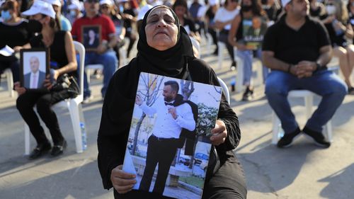 The mother of a victim who was killed in the massive blast last year at the Beirut port holds a portrait of her son as she attends a Mass held to commemorate the first year anniversary.