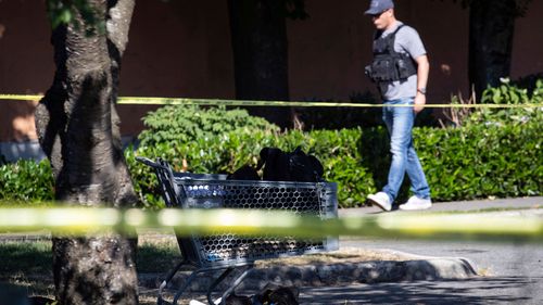A shopping cart with a person's belongings is seen behind police tape at one of three locations being investigated in regards to multiple shootings in Langley, British Columbia.