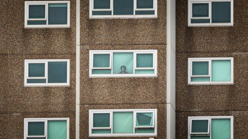 A lone woman is seen looking out the window of her apartment at the North Melbourne Public housing flats on July 05, 2020 in Melbourne, Australia. Nine public housing estates have been placed into mandatory lockdown and two additional suburbs are under stay-at-home orders as authorities work to stop further COVID-19 outbreaks in Melbourne. 