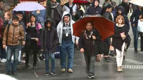 Pedestrians struggle to avoid the rain in Melbourne's CBD. (9NEWS)