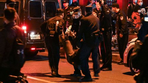 Seorang pria ditangkap saat orang-orang berkumpul di sebuah jalan di Shanghai pada 27 November.