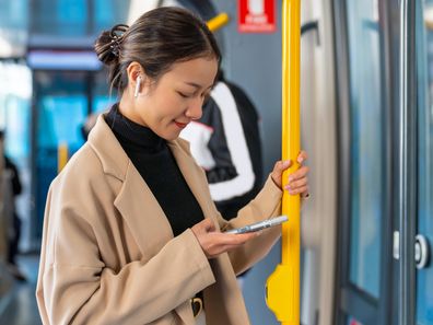 Young woman listening to music on her phone on a bus