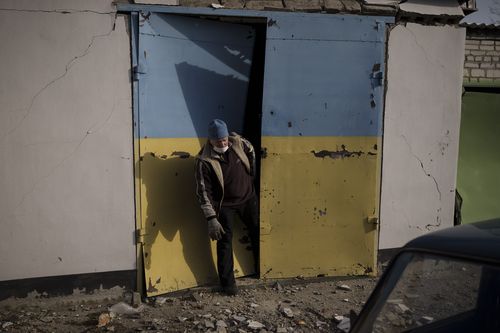 A man tries to open a door damaged after a Russian bombing in Baryshivka, east of Kyiv, Ukraine, Friday, March 11, 2022
