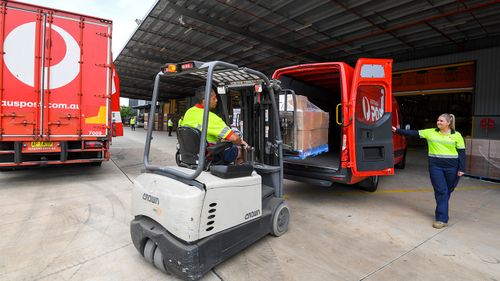 Workers pack Australia Post delivery trucks and vans