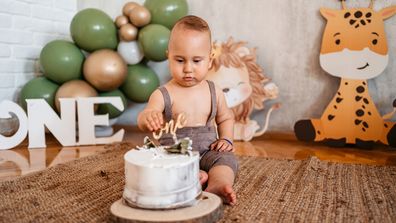 Baby boy celebrating his first birthday with a cake and balloons.