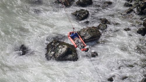 An injured man is winched across the river. Photo: AAP