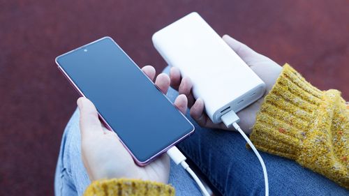 Smartphone in hand is charging from power bank