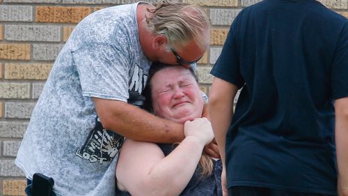 A man hugged a woman outside the Alamo Gym where parents waited to reunite with their children. Picture: AP