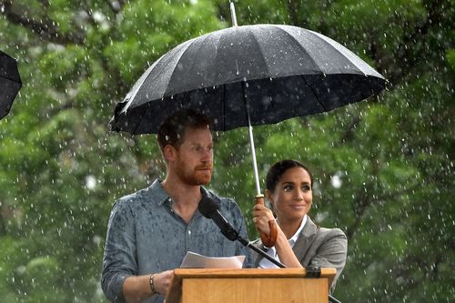 Meghan held an umbrella over Harry's head as he delivered his speech in driving rain.