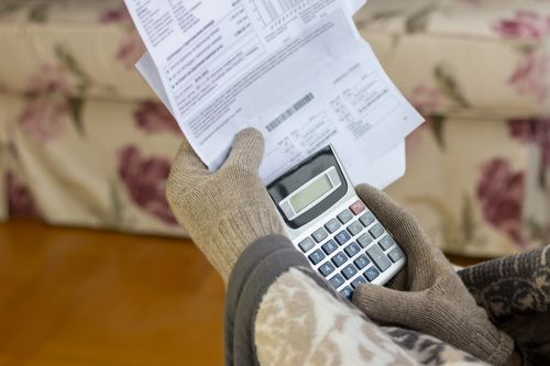 Uomo maturo preoccupato che legge la lettera di notifica di interruzione di corrente, tiene in mano la bolletta del riscaldamento, è confuso e stupito da notizie incredibili: fattura fiscale elevata, notifica di debito, cattivo rapporto finanziario, problema di soldi