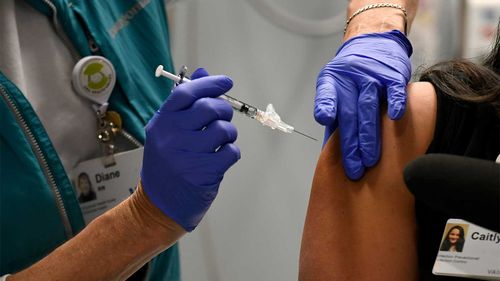 A mock COVID-19 vaccine is given to a health staffer at a hospital in Colorado.
